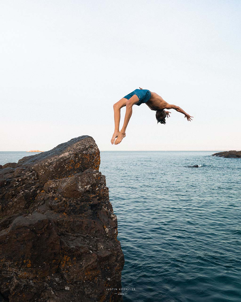 Man backflipping off of cliff into the ocean