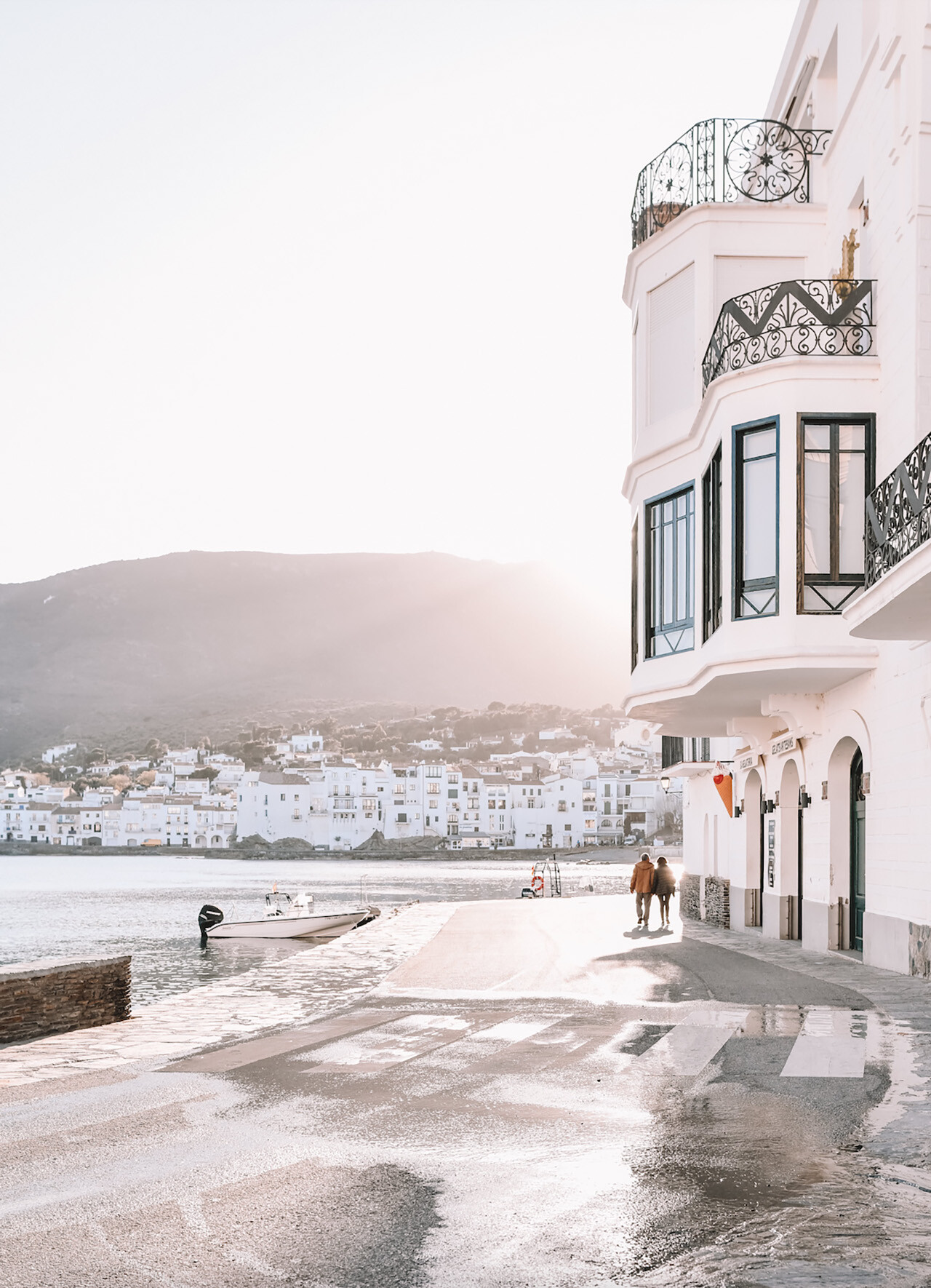 White building on water with bright sun behind it